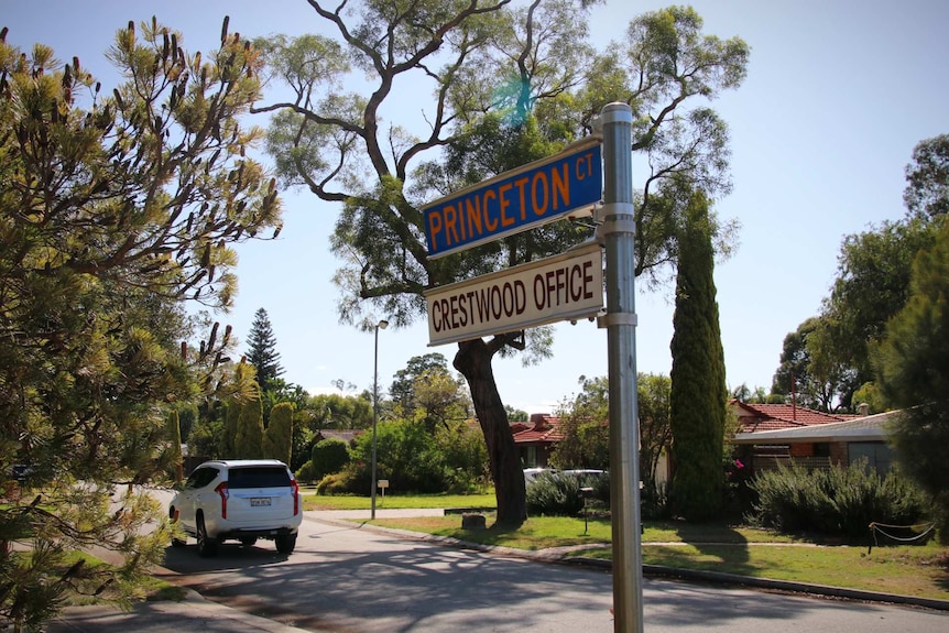 A street sign points to a neat tree lined suburban road