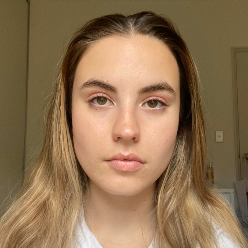 A young woman with blonde hair and brown eyes looks straight into the camera with a serious expression