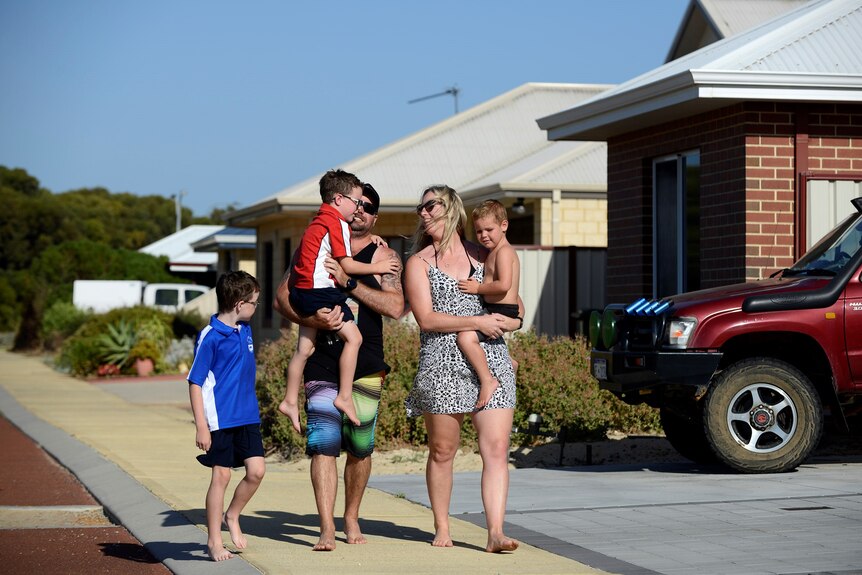 A family of five walk down a neat subdivision street