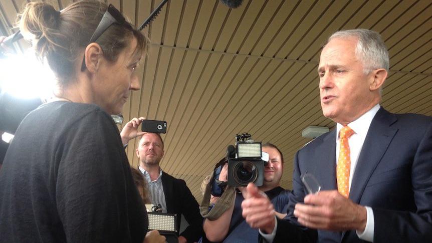 A woman talks to Malcolm Turnbull while surrounded by members of the media.