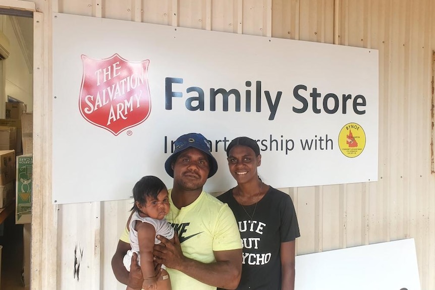 A young Aboriginal family stands infront of a big sign that reads Salvation Army Family Store