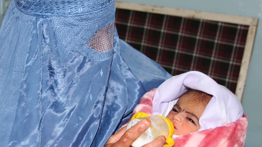 Afghan woman feeds her newly adopted baby rescued by Polish troops