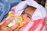 Afghan woman feeds her newly adopted baby rescued by Polish troops