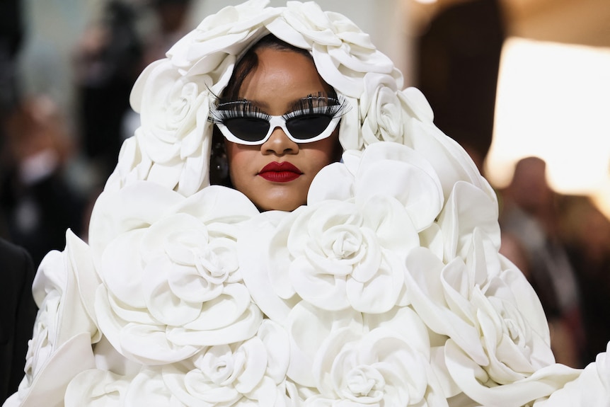 Rihanna attends the Met Gala in an all white dress that surrounds her face.
