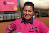 Heather Jones in a pink work shirt standing in front of her out of focus pink road train