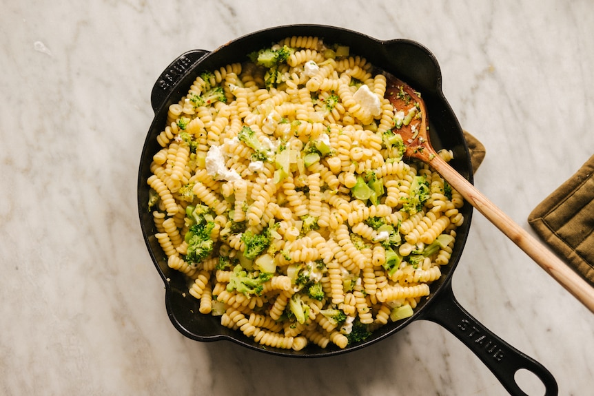 Frying pan of broccoli, fusilli pasta with feta cheese. An easy weeknight dinner that is vegetarian.