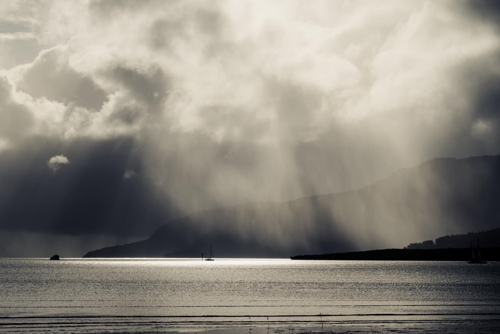Rain falling over ocean with mountains in background