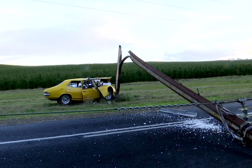 A car crumpled against a power pole which has split and fallen.