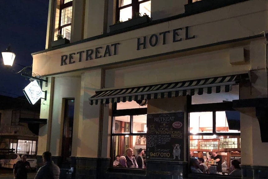 The outside of a pub at night with diners seen through the window.