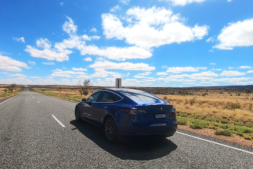 An electric car drives on a remote highway.