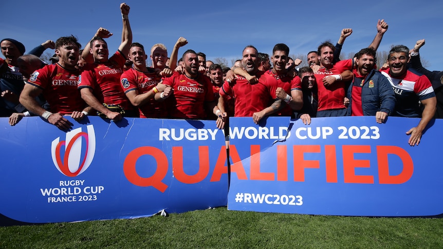 The Spanish rugby union team cheers and celebrates behind a sign saying "Rugby World Cup 2023 Quailfied"