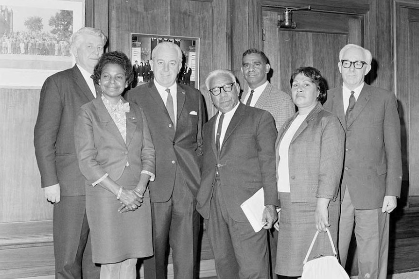 Black and white photo of a group of well-dressed black and white people posing formally for the camera