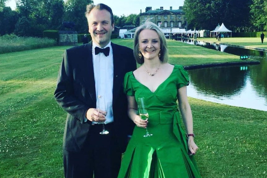 A man in a suit and kilt stand next to a woman in a green dress.