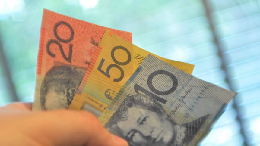 A hand holds Australian bank notes