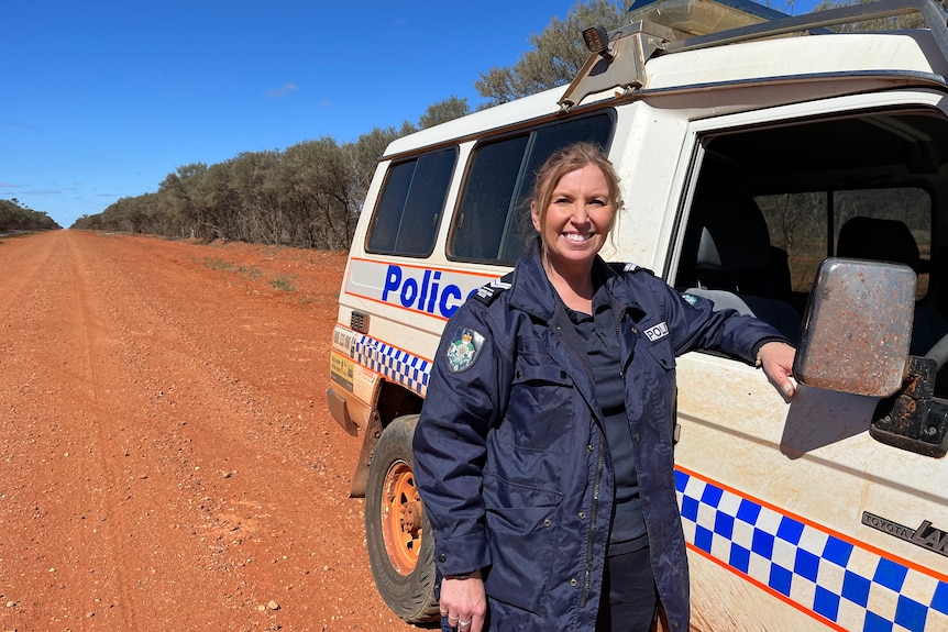 A female police officer standing next to a 4WD police vehicle on an outback road