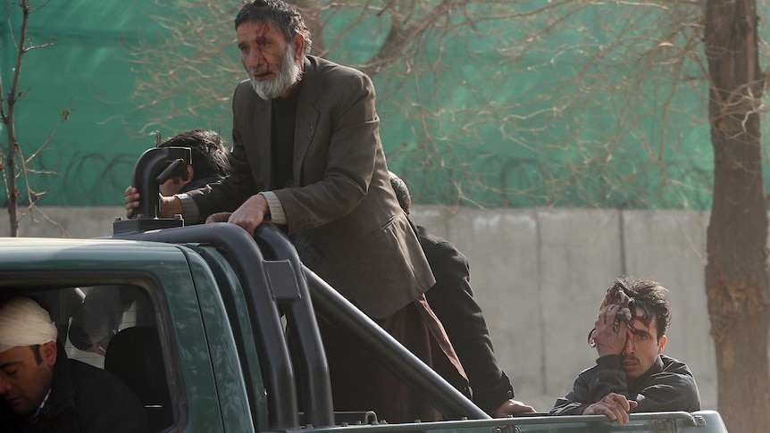 Wounded civilians are transferred to a hospital in the back of a police vehicle after a deadly suicide attack