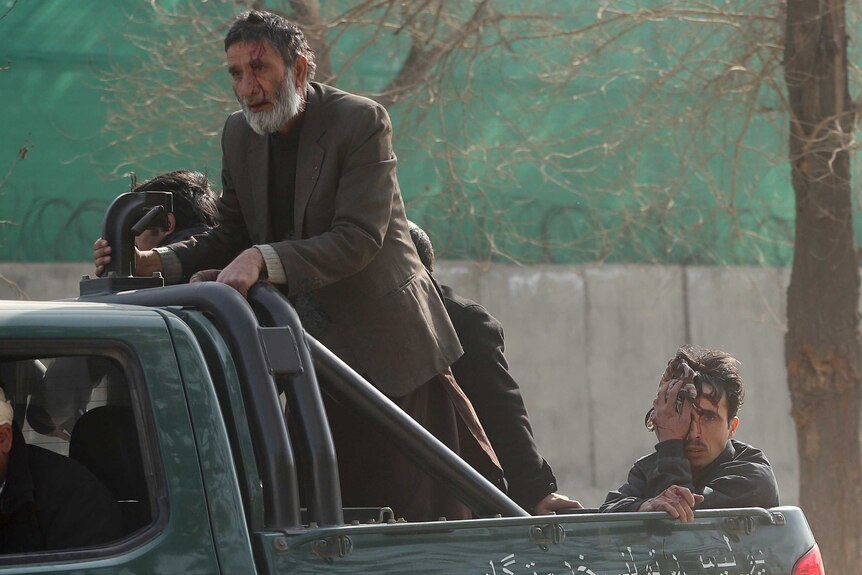 Wounded civilians are transferred to a hospital in the back of a police vehicle after a deadly suicide attack