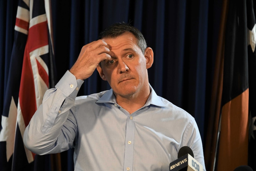 Michael Gunner stands at a lectern scratching his head