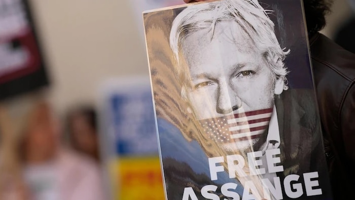 A person holding a free Julian Assange poster, protesting his extradition to the US