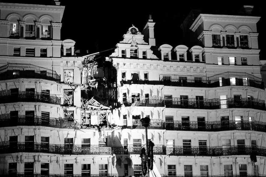A black and white photo of a grand hotel facade, with several floors damaged by a bomb
