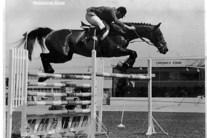 A black and white image of a rider showjumping double oxer
