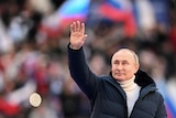 Putin waves to crowd wearing black puffer jacket.