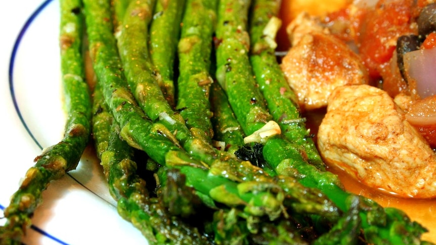 A cooked dish with a side of asparagus.