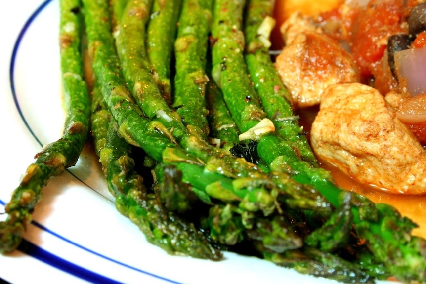 A cooked dish with a side of asparagus.