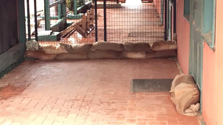 Sandbags on the ground outside a gate and a door on the patio of a property in Whim Creek.