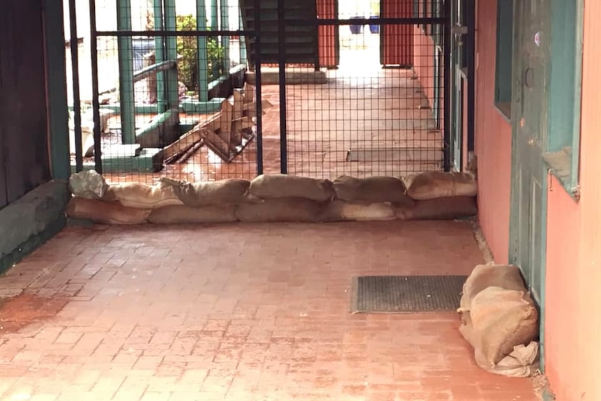 Sandbags on the ground outside a gate and a door on the patio of a property in Whim Creek.