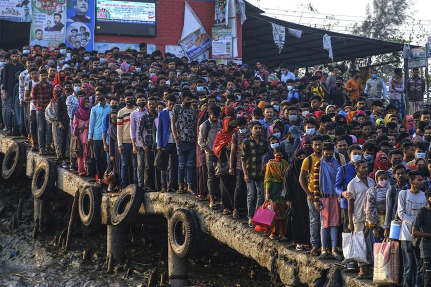 Hundreds, possibly thousands of workers gather in the morning at a boat terminal 