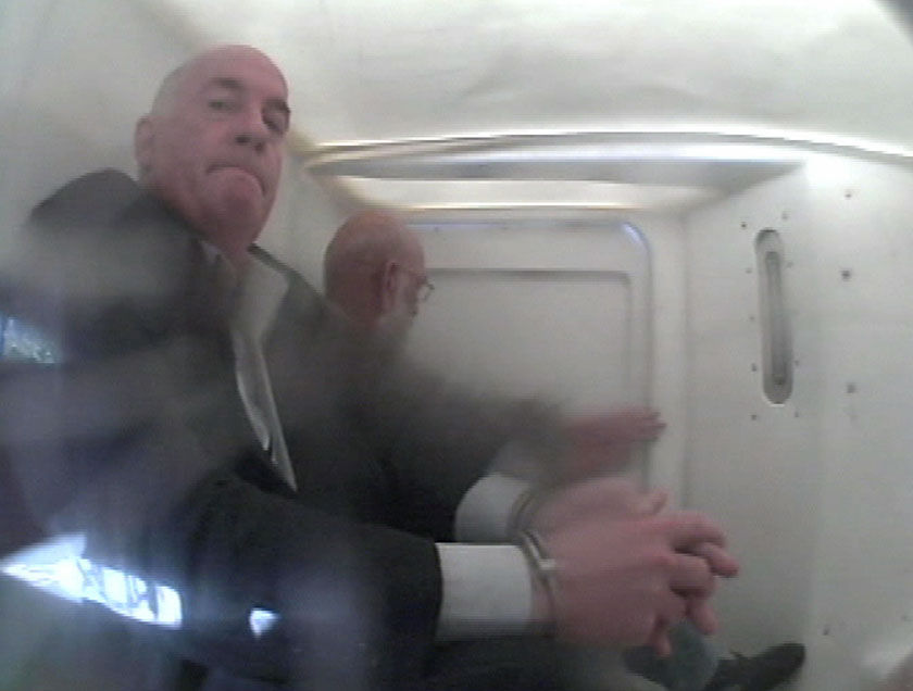 Grainy TV still of former Qld Govt Minister Gordon Nuttall sitting handcuffed in police van