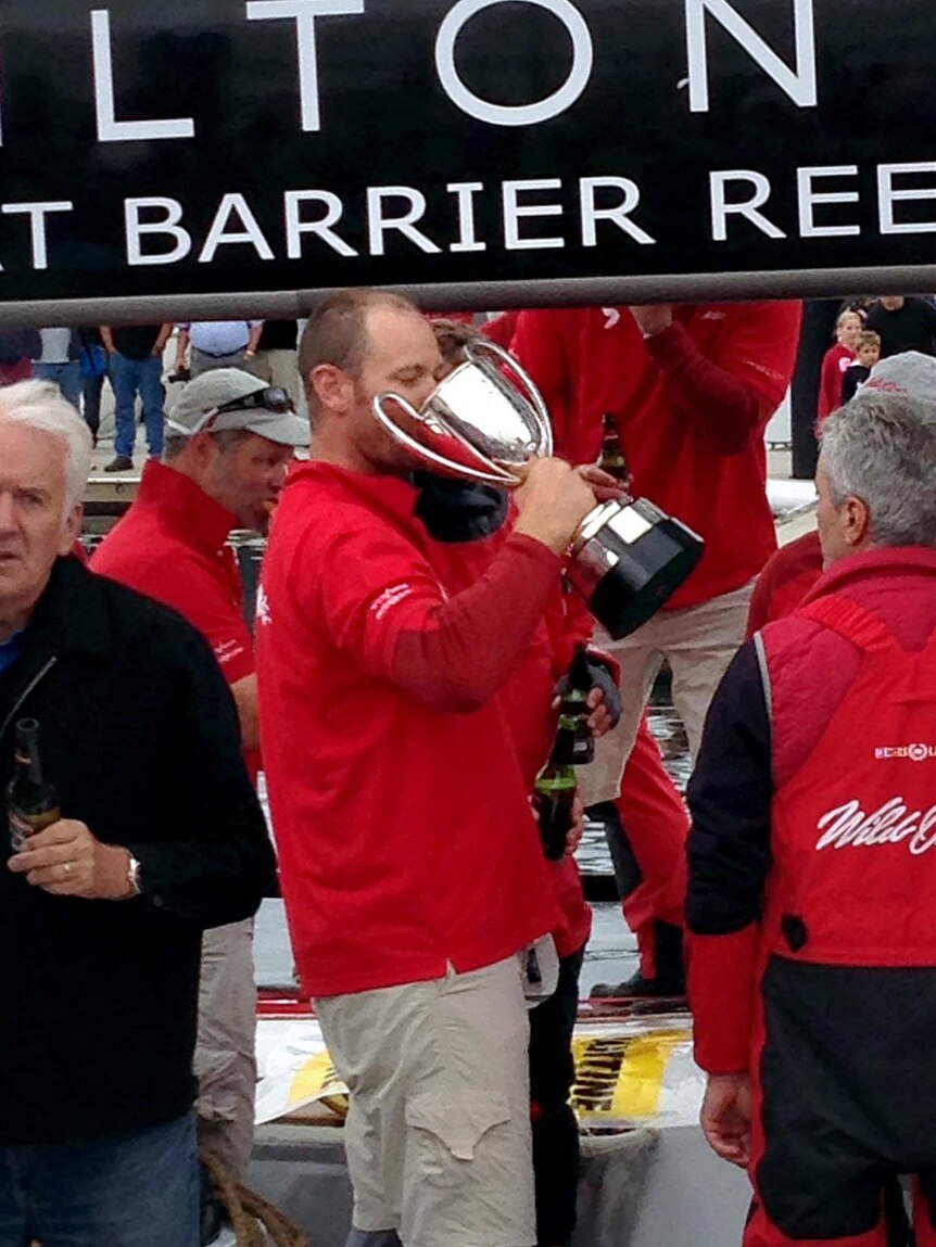 Victory is sweet ... a Wild Oats XI crew member takes a sip from the trophy.