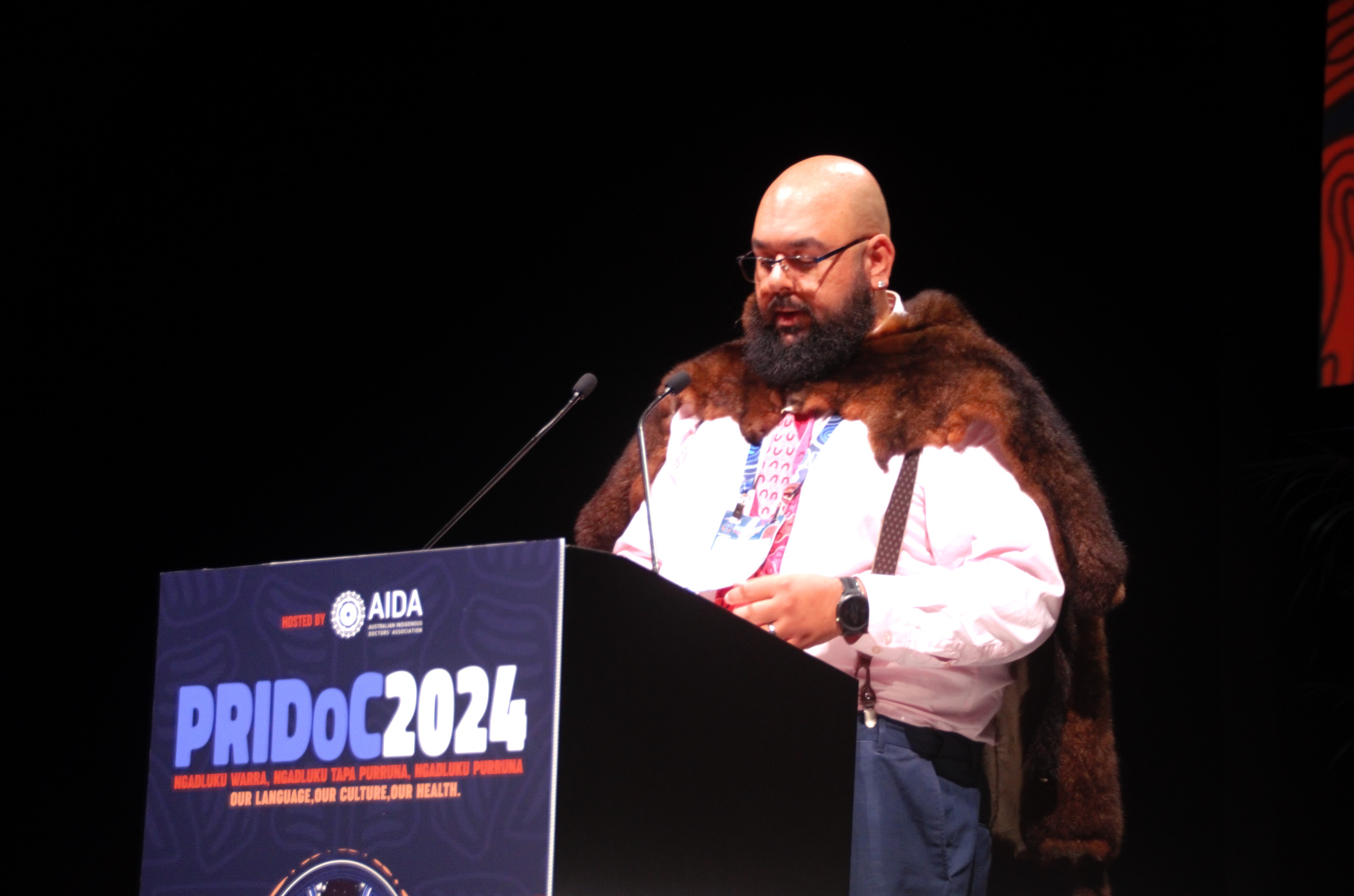 Dr Newchurch standing at a podium, speaking into a microphone