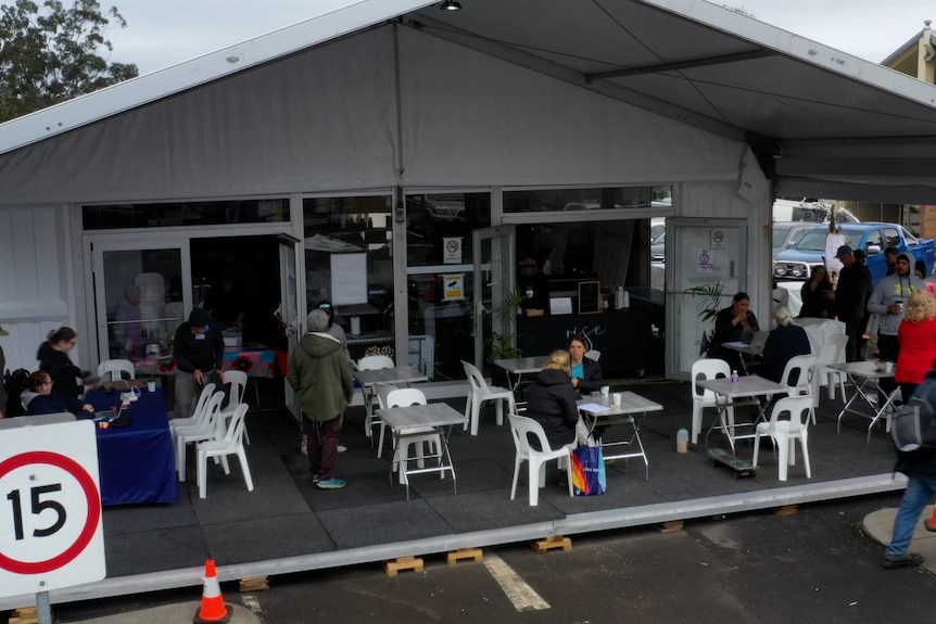 A white marquee with tables and chairs and people around