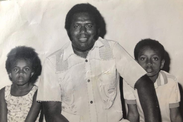 Black and white photo of a man with two children, one on either side of him.