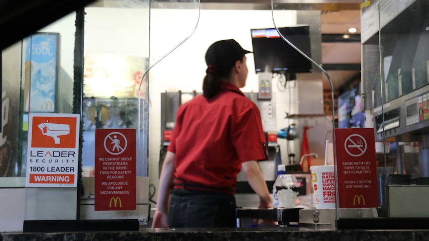 A McDonald's worker stands in drive through window in Manuka
