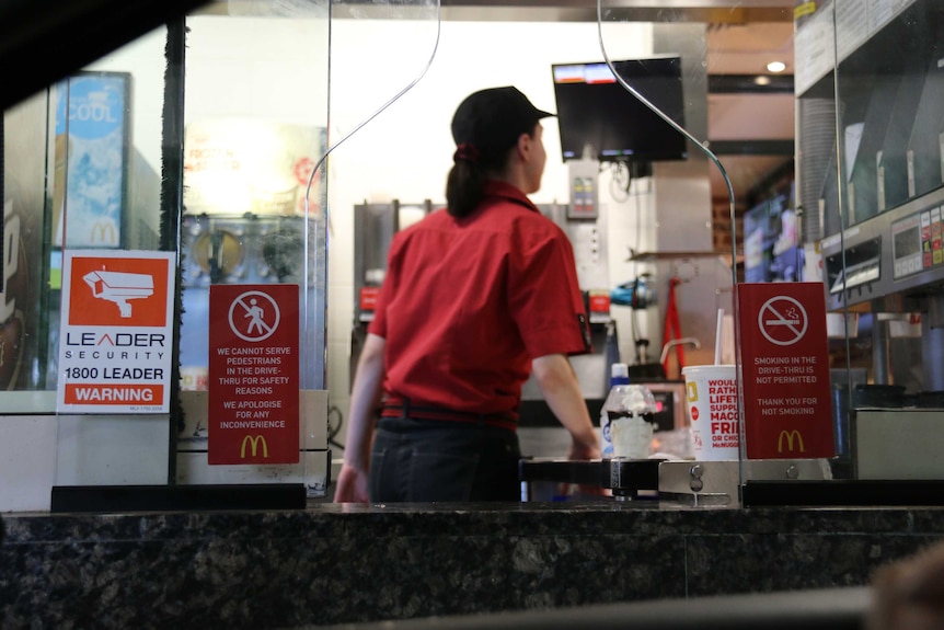 A McDonald's worker stands in drive through window in Manuka