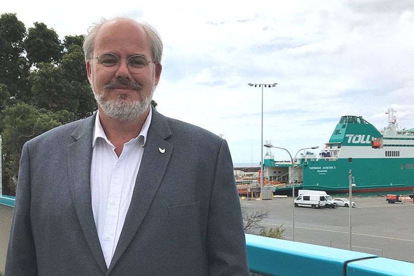 Brett Charlton stands in front to the new Toll ship Tasmanian Achiever Two