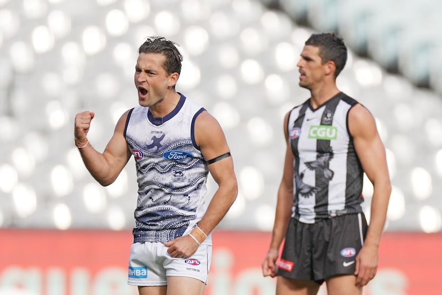 Geelong Cat Luke Dahlhaus pumps his fist in celebration in front of Collingwood Magpie Scott Pendlebury.