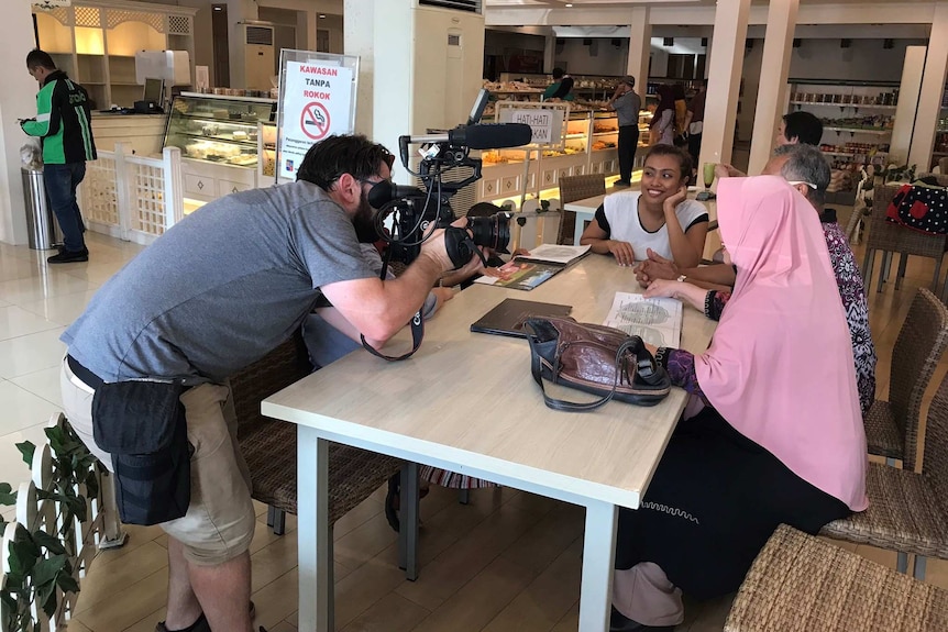 Cameraman filming women in cafe.