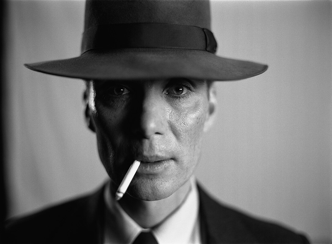 black and white close up photo of man's face - wearing hat and cigarette hanging out of mouth