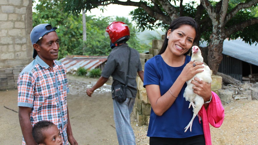 East Timorese man holds a white hen in the village of Saburai, East Timor