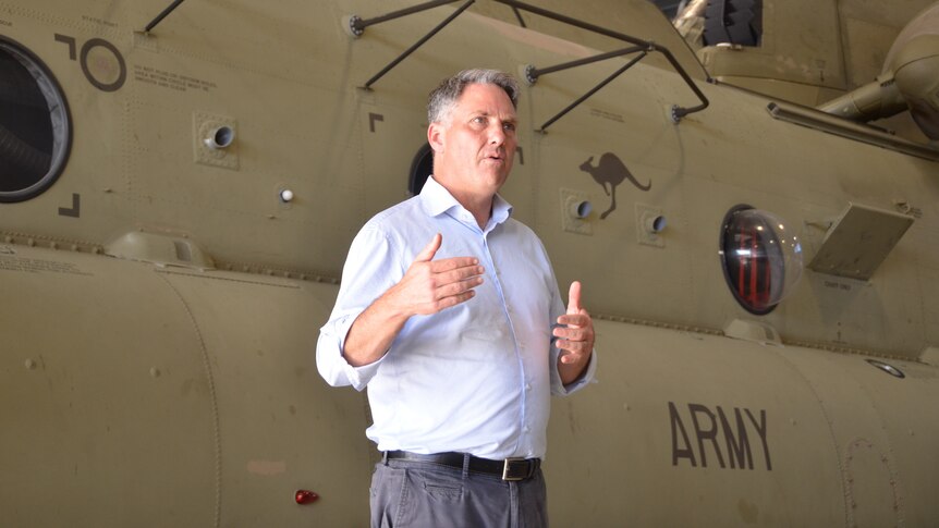 Marles stands in front of a military aircraft speaking to media.