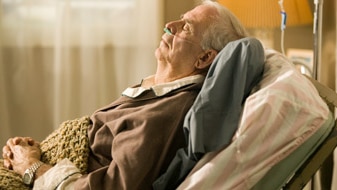 Senior man lying in bed in retirement home with tubes in nose (Thinkstock:  Photodisc)