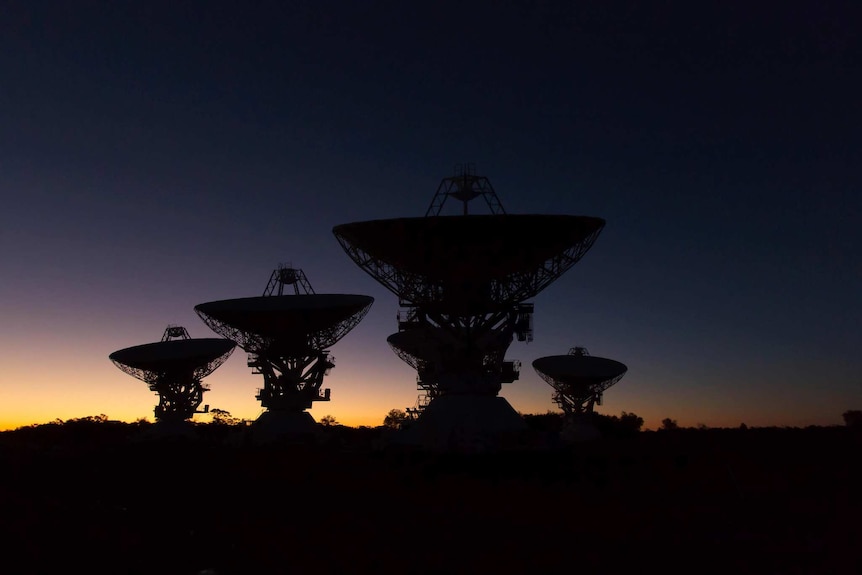 Four large telescope dishes at twilight