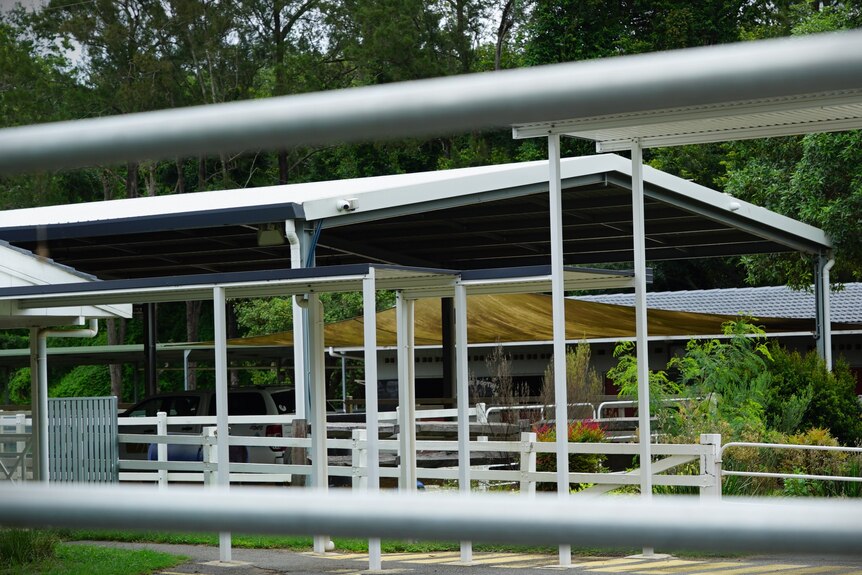 Empty horse stalls through a fenceline. 