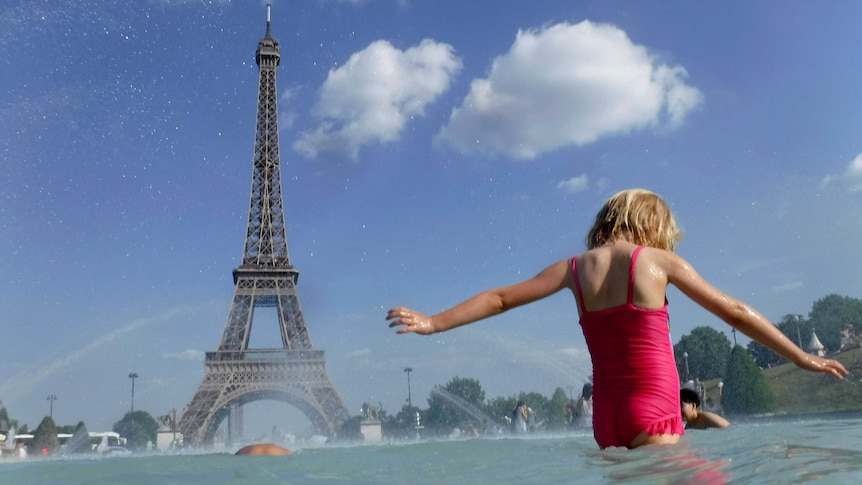 A girl cools off in the fountain in front of the Eiffel Tower.