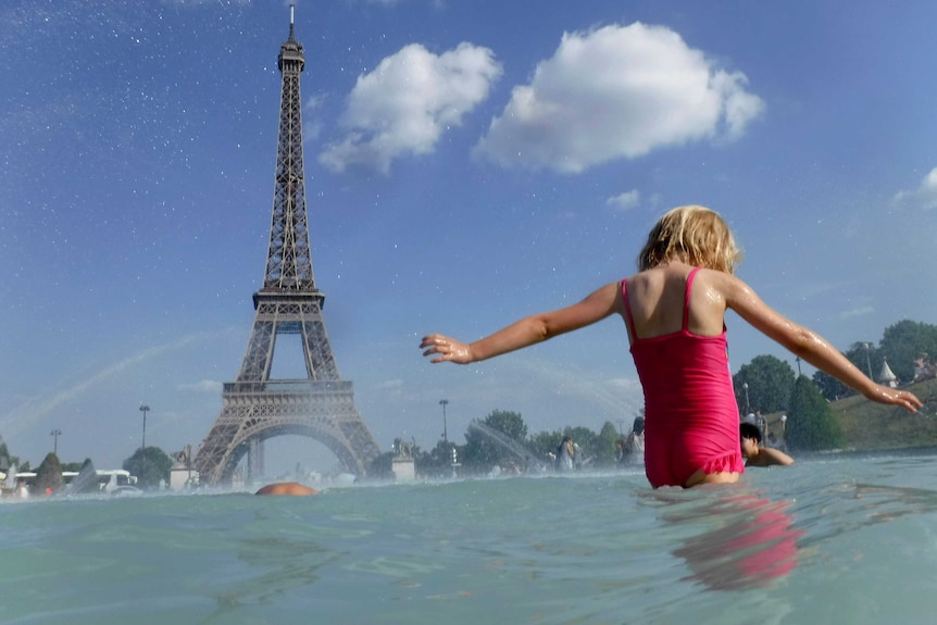 A girl cools off in the fountain in front of the Eiffel Tower.