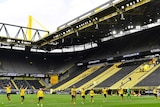 Borussia Dortmund players stand inside an empty stadium at the end of a Bundesliga match.